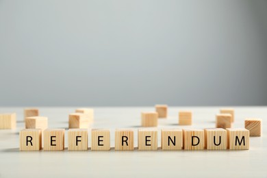 Word Referendum of wooden cubes on white table against light grey background. Space for text