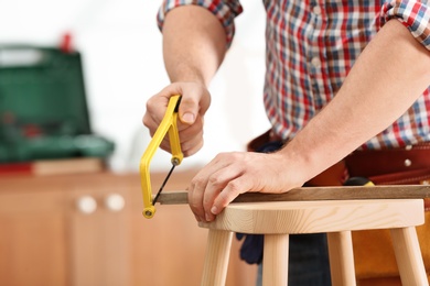 Man working with hand saw indoors, closeup. Home repair