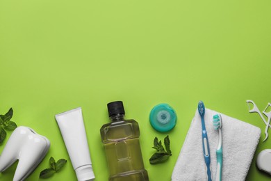 Flat lay composition with mouthwash and other oral hygiene products on light green background. Space for text