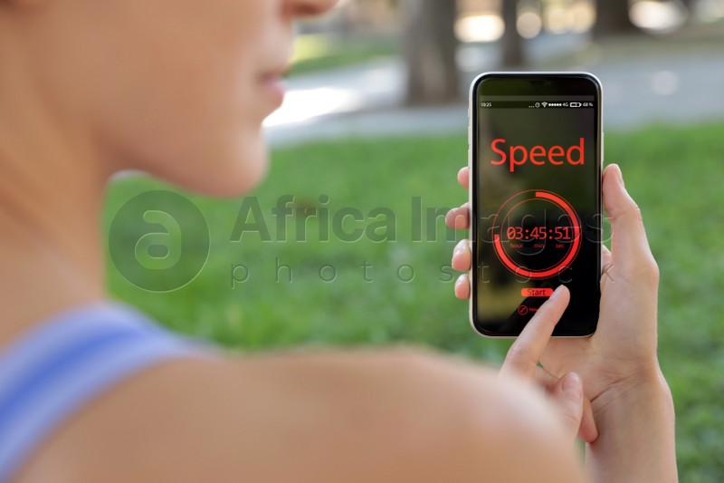 Photo of Young woman using fitness app on smartphone in park, closeup