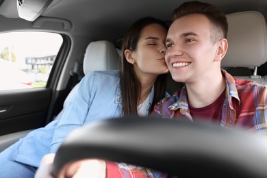 Photo of Young woman kissing her boyfriend in car