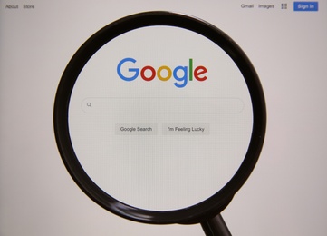 MYKOLAIV, UKRAINE - OCTOBER 30, 2020: Looking through magnifying glass at screen with Google search bar