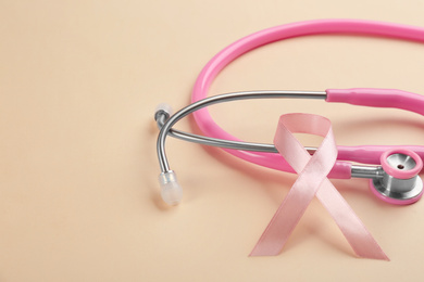 Pink ribbon and stethoscope on beige background, closeup. Breast cancer concept