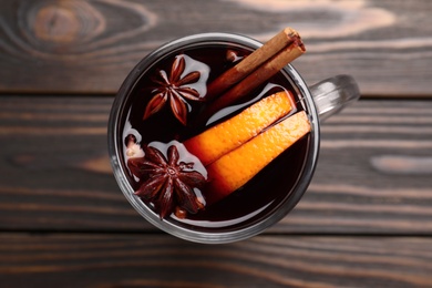 Cup with mulled wine on wooden table, top view
