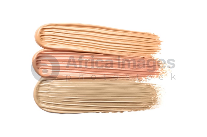 Different shades of liquid foundation on white background, top view