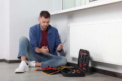 Man choosing wrench near box with tools indoors