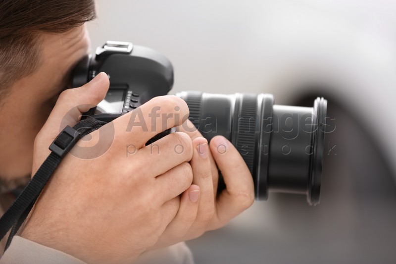 Male photographer with professional camera on blurred background, closeup