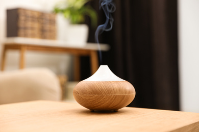Photo of Aroma oil diffuser on wooden table at home. Air freshener
