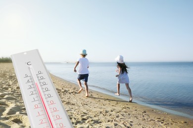 Weather thermometer and little children running on sandy beach. Heat stroke warning