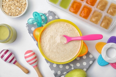 Flat lay composition with bowl of healthy baby food on white background