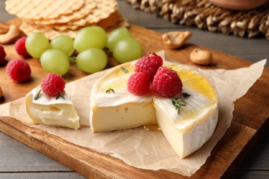 Brie cheese served with berries on wooden table, closeup