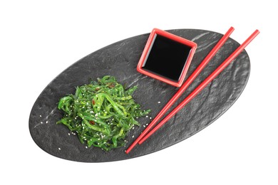 Slate plate with Japanese seaweed salad, soy sauce and chopsticks isolated on white, top view