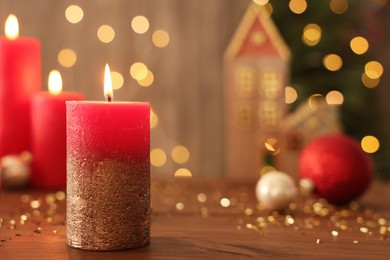 Beautiful burning candles with Christmas decor on wooden table against blurred festive lights, space for text