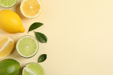 Fresh ripe lemons, limes and green leaves on beige background, flat lay. Space for text