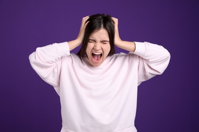 Portrait of stressed young woman on purple background