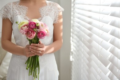 Bride with beautiful ranunculus bouquet indoors, closeup. Space for text