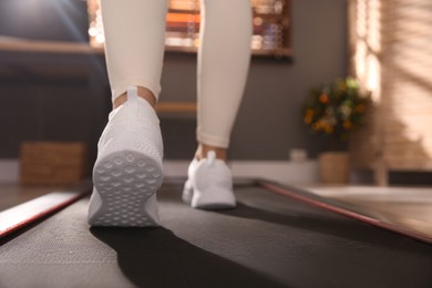 Sporty woman training on walking treadmill at home, closeup
