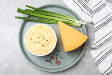 Tasty cheese sauce with green onion and peppercorns on light grey table, top view