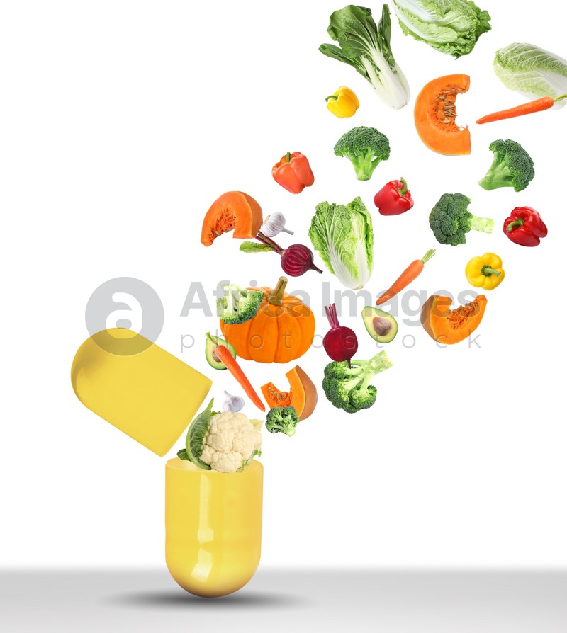 Dietary supplements. Capsule and different fresh vegetables flying on white background