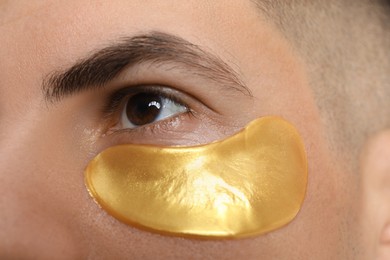 Man with golden under eye patch, closeup