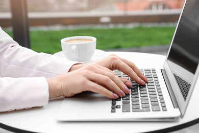 Photo of Businesswoman working with laptop in outdoor cafe, closeup. Corporate blog