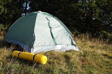Photo of Sleeping mat near camping tent outdoors. Tourism equipment