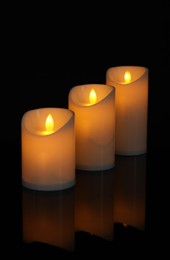 Glowing decorative LED candles on black background