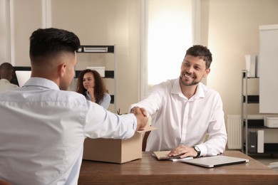 Employee shaking hand with new coworker in office