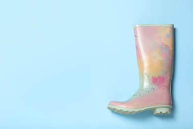 Colorful rubber boot on light blue background, top view. Space for text