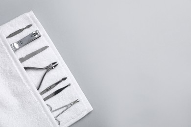 Photo of Towel with set of manicure tools on grey background, top view. Space for text