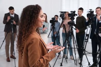 Photo of Happy African American business woman talking to group of journalists indoors