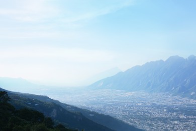 Photo of Big city between mountains under sky on sunny day