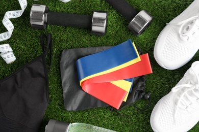 Flat lay composition with fitness elastic bands on green grass