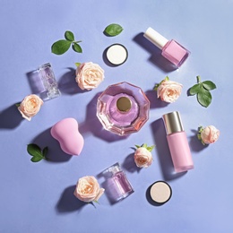 Flat lay composition with bottles of perfume, cosmetics and roses on color background