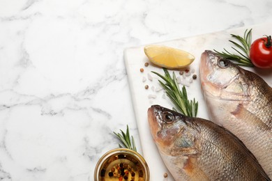 Fresh raw perches and ingredients on white marble table, flat lay with space for text. River fish