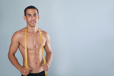 Handsome shirtless man with slim body and measuring tape on grey background. Space for text