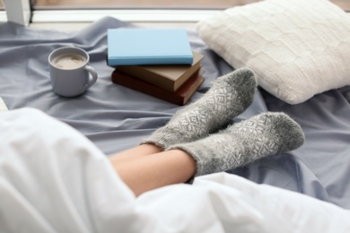 Young woman lying on bed, closeup view of legs. Winter atmosphere