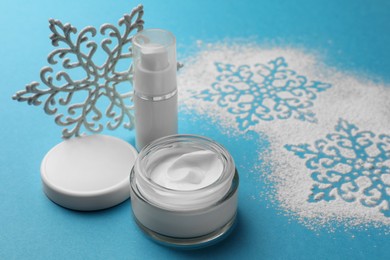Photo of Set of cosmetic products with hand cream and Christmas decor on light blue background, space for text. Winter skin care