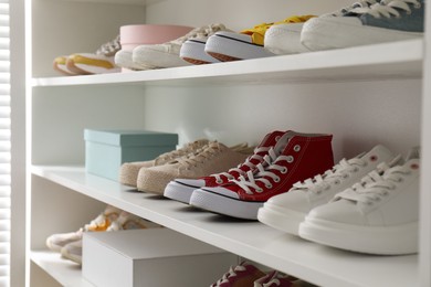 Photo of White shelving unit with collection of colorful sneakers indoors
