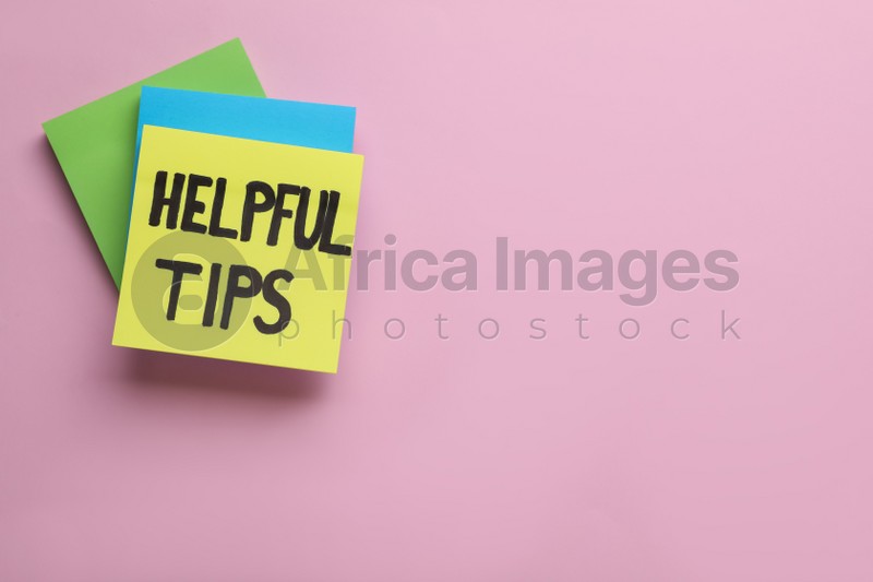 Photo of Paper note with phrase Helpful Tips on pink background, top view. Space for text