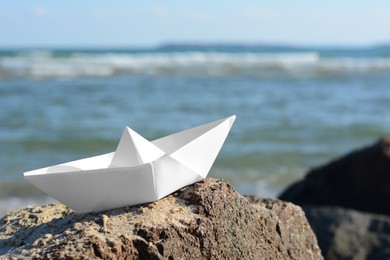 White paper boat on rock near sea, space for text