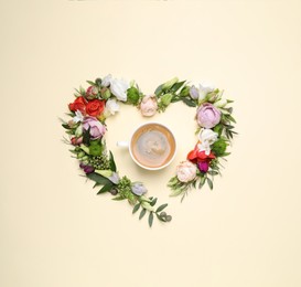 Beautiful heart made of different flowers and coffee  on beige background, flat lay