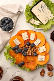 Photo of Delicious persimmon with blue cheese on white marble table, flat lay