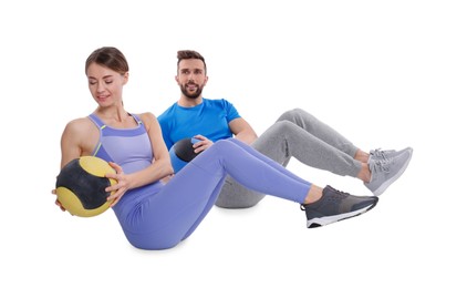 Athletic couple doing exercise with medicine balls on white background