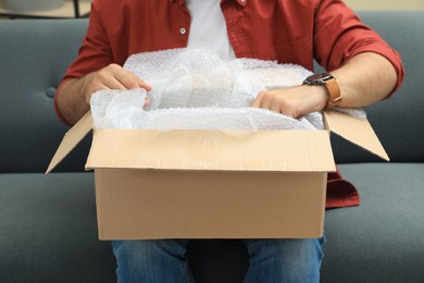 Man unpacking parcel at home, closeup. Online shopping