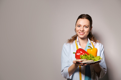 Nutritionist with healthy products on light grey background. Space for text