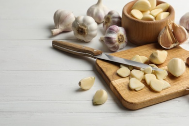 Fresh organic garlic on white wooden table. Space for text