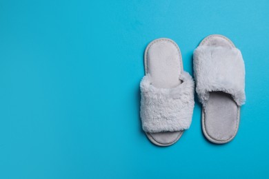 Pair of soft fluffy slippers on blue background, top view. Space for text
