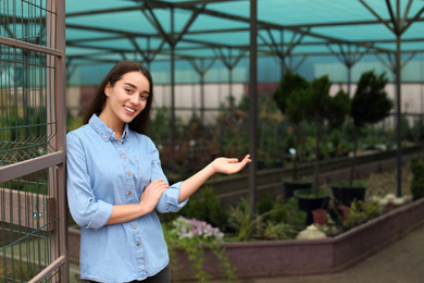 Photo of Female business owner showing her greenhouse. Space for text