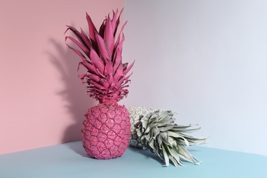 Photo of Pink and white pineapples on color background, space for text. Creative concept